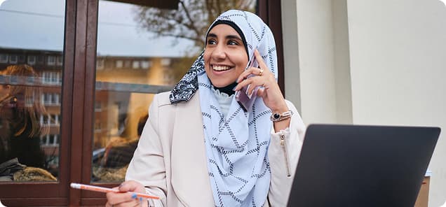 Woman smiling on the phone with a laptop