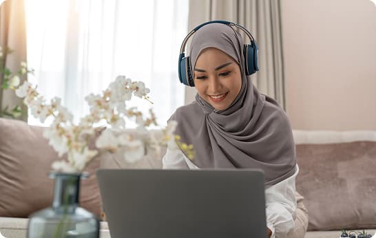 Woman setting up online store on laptop with headphones