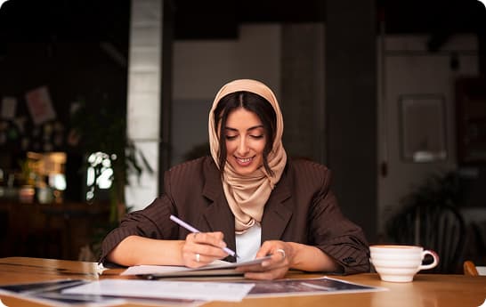 Woman working at a desk, writing on paper
